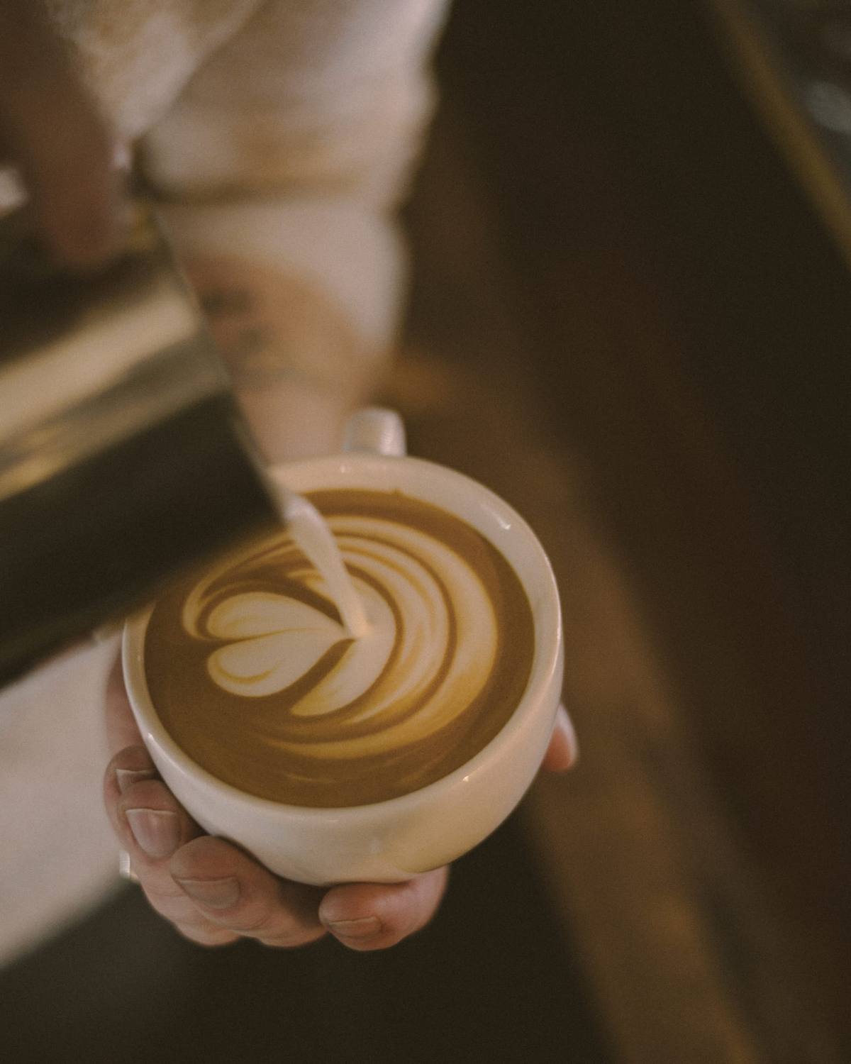 Frisch gegossenes Latte-Art, von Hand serviert